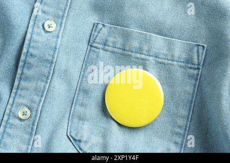 Gelbes Knopfabzeichen am Jeansshirt, Draufsicht. Modell für Design Stockfoto