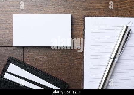 Kartenhalter aus Leder mit leeren Visitenkarten, Notizbuch und Stift auf Holztisch, flach gelegt. Modell für Design Stockfoto