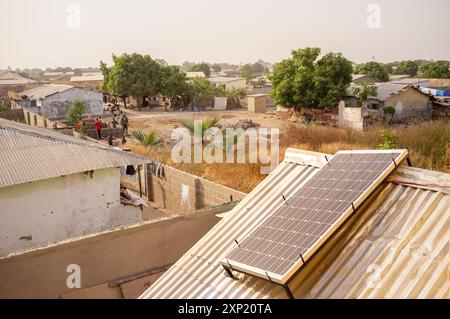 Blick auf ein ländliches Dorf in Gambia, Westafrika, mit Solarpaneelen auf Dächern als Metapher für erneuerbare Energien und nachhaltiges Wohnen. Stockfoto