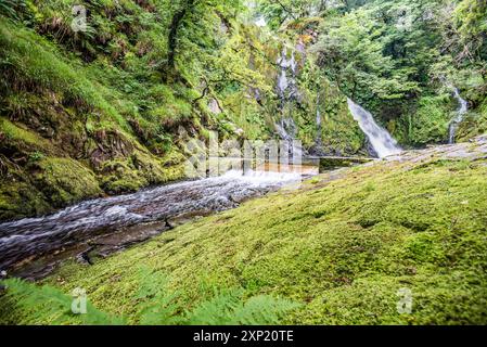 Ein 'unterer Pfad' führt entlang eines Buckels, mit mehreren kleinen Wasserfällen und weißem Wasser, der am hohen Wasserfall des Ceunant Mawr in Llanberis endet. Stockfoto