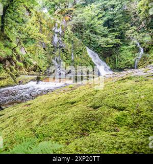 Ein 'unterer Pfad' führt entlang eines Buckels, mit mehreren kleinen Wasserfällen und weißem Wasser, der am hohen Wasserfall des Ceunant Mawr in Llanberis endet. Stockfoto