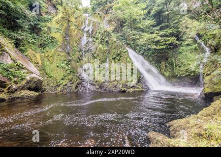 Ein 'unterer Pfad' führt entlang eines Buckels, mit mehreren kleinen Wasserfällen und weißem Wasser, der am hohen Wasserfall des Ceunant Mawr in Llanberis endet. Stockfoto