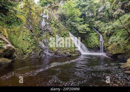 Ein 'unterer Pfad' führt entlang eines Buckels, mit mehreren kleinen Wasserfällen und weißem Wasser, der am hohen Wasserfall des Ceunant Mawr in Llanberis endet. Stockfoto