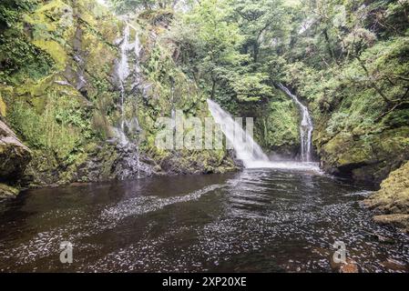 Ein 'unterer Pfad' führt entlang eines Buckels, mit mehreren kleinen Wasserfällen und weißem Wasser, der am hohen Wasserfall des Ceunant Mawr in Llanberis endet. Stockfoto