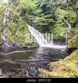 Ein 'unterer Pfad' führt entlang eines Buckels, mit mehreren kleinen Wasserfällen und weißem Wasser, der am hohen Wasserfall des Ceunant Mawr in Llanberis endet. Stockfoto