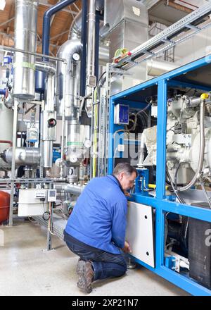 Ein Techniker, der Maschineneinstellungen in einem Blockheizkraftwerk am St. Georg Hospital in Leipzig durchführt. Die Anlagen sind mit modernen Systemen zur Förderung von Energieeffizienz und Nachhaltigkeit ausgestattet. Stockfoto