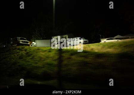 Vorstadtszene mit Häusern und geparkten Autos, die von einer Straßenlaterne beleuchtet werden, symbolisiert Ruhe und Stille einer Nacht in der Nachbarschaft. Stockfoto