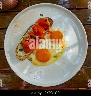 Geräucherter Lachs auf Toast mit Spiegeleiern zum Frühstück in einem Restaurant während des Urlaubs. Stockfoto