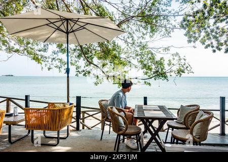 Ein Teenager saß in einem Restaurant mit Blick auf den Strand Tanjing Tokong in Penang, Malaysia Stockfoto