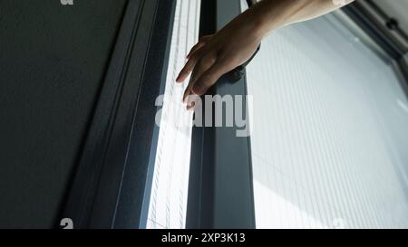 Eine Nahaufnahme einer Hand, die eine Glasschiebetür öffnet. Stockfoto