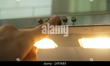 Eine Nahaufnahme einer Hand, die einen Knopf an einer Küchenpaddelbox drückt, um das Licht einzuschalten. Die Funktionalität und Benutzerfreundlichkeit des Küchengeräts. Stockfoto