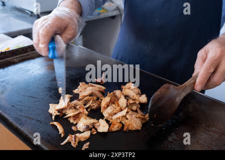 Ein Koch schneidet Fleisch mit einem Messer für einen Street Food Döner Döner oder Shawarma. Stockfoto