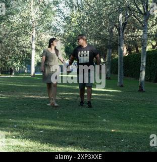 Ein Mann und eine Frau laufen in einem Park. Der Mann trägt ein schwarzes Hemd und die Frau ein grünes Kleid Stockfoto