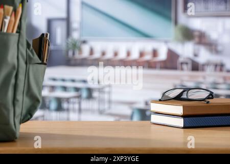 Schulsachen und Rucksack auf der Schulbank im Klassenzimmer. Verschwommener Hintergrund der Tafel an Wand und Fenster mit Sonnenlicht. Stockfoto