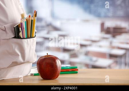 Schulsachen und Rucksack auf der Schulbank im Klassenzimmer. Verschwommener Hintergrund der Tafel an Wand und Fenster mit Sonnenlicht. Stockfoto