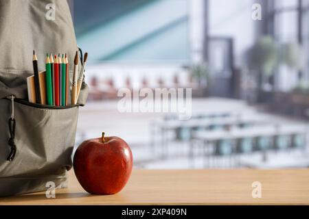 Schulsachen und Rucksack auf der Schulbank im Klassenzimmer. Verschwommener Hintergrund der Tafel an Wand und Fenster mit Sonnenlicht. Stockfoto
