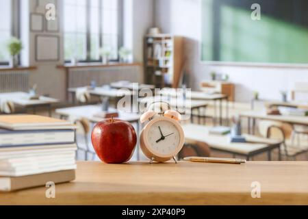 Schulsachen und Rucksack auf der Schulbank im Klassenzimmer. Verschwommener Hintergrund der Tafel an Wand und Fenster mit Sonnenlicht. Stockfoto