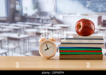 Schulsachen und Rucksack auf der Schulbank im Klassenzimmer. Verschwommener Hintergrund der Tafel an Wand und Fenster mit Sonnenlicht. Stockfoto