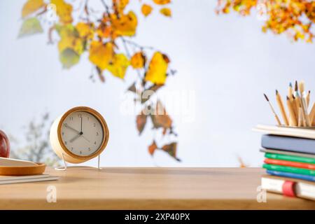 Schulrucksack und Schulsachen mit Platz für Produkte auf hölzernem Schreibtisch mit Herbstbaum und blauem Himmel Hintergrund. Zurück zur Schule. Kopierraum für Schule Stockfoto