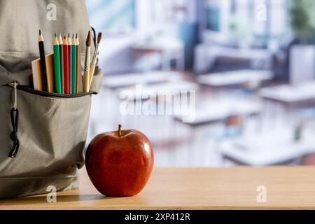 Schulsachen und Rucksack auf der Schulbank im Klassenzimmer. Verschwommener Hintergrund der Tafel an Wand und Fenster mit Sonnenlicht. Stockfoto