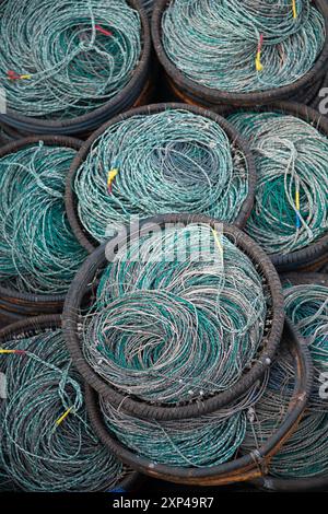 Nahaufnahme von gewickelten Fischernetzen in runden Körben, die komplexe Webkunst und leuchtende Farben zeigen. Stockfoto