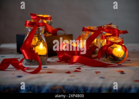 Kerzenlicht in Glasgläsern mit roten Bändern für eine gemütliche festliche Atmosphäre Stockfoto