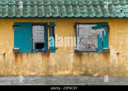Baufälliges Gebäude mit kaputten Fenstern und abblätternder Farbe, die urbanen Verfall zeigt Stockfoto
