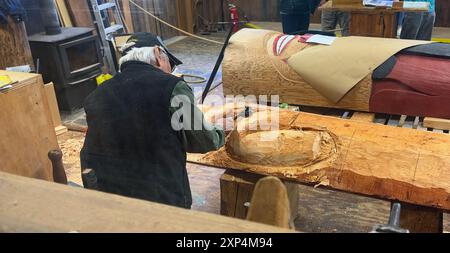 Ein Meisterschnitzermeister arbeitet an einem neuen Totempfahl im Saxman Totem Park in der Werkstatt, die für Besucher geöffnet ist. Stockfoto