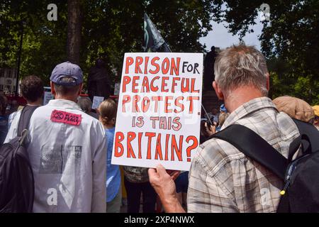 London, Großbritannien. August 2024. Ein Demonstrant hält ein Plakat mit der aufschrift "Gefängnis für friedlichen Protest - ist das Großbritannien?" Während der Demonstration auf dem Parliament Square. Die Demonstranten versammelten sich in Solidarität mit 21 Just Stop Ölaktivisten, die derzeit wegen verschiedener Klimaproteste im Gefängnis sind. Quelle: SOPA Images Limited/Alamy Live News Stockfoto