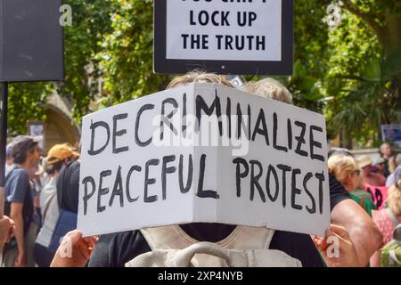 London, Großbritannien. August 2024. Ein Demonstrant hält während der Demonstration auf dem Parlamentsplatz ein Plakat mit dem Titel „Entkriminalisierung friedlicher Proteste“. Die Demonstranten versammelten sich in Solidarität mit 21 Just Stop Ölaktivisten, die derzeit wegen verschiedener Klimaproteste im Gefängnis sind. Quelle: SOPA Images Limited/Alamy Live News Stockfoto