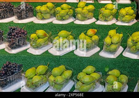 Grüne Birnen und schwarze Trauben im Supermarktregal. Stockfoto