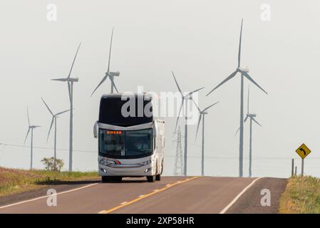 Doppeldeckerbus auf Landstraße mit Windturbinen in nebeliger Umgebung Stockfoto