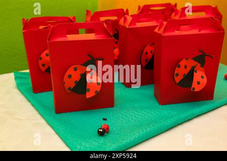 Rote Partytaschen mit Marienkäfern auf einem leuchtend grünen und gelben Hintergrund Stockfoto