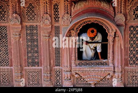 Ein Mann mit einem Turbant, der sich an einem Fenster in Mehrangarh Fort, Jodhpur, Rajasthan, Indien lehnt Stockfoto