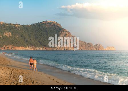 Ein paar Spaziergänge entlang eines leeren Kleopatra-Strandes bei Sonnenuntergang im türkischen Ferienort Alanya an der türkischen Mittelmeerküste, der türkischen Riviera. Stockfoto