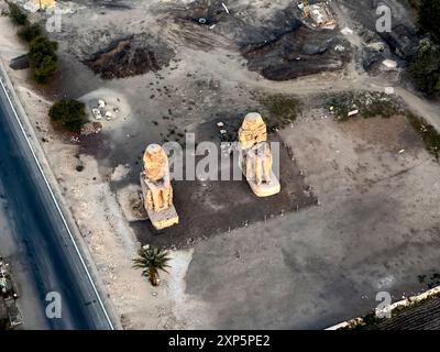 Erleben Sie die Majestät der Memnon Kolosse wie nie zuvor. Dieses atemberaubende Luftbild fängt die kolossalen Statuen von Amenhotep III. Ein. Stockfoto