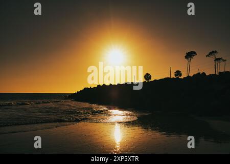 Sonnenuntergang mit Lichtstrahlen, die auf nassem Sand und Rock Jetty am Cape San Blas, Florida, USA, reflektieren Stockfoto