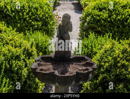 Kleines künstlerisches Vogelbad mit Engelsstatue in wunderschön gepflegtem Garten Stockfoto