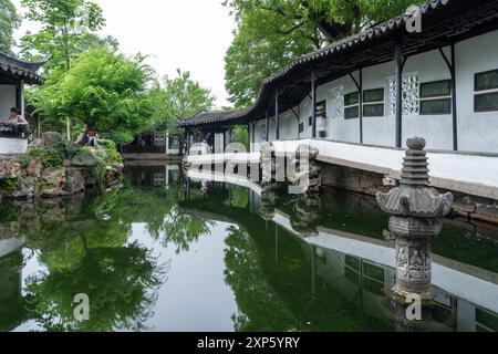 Suzhou, China - 11. Juni 2024 : Ein heiterer Teich spiegelt die Architektur des Garten des bescheidenen Administrators in Suzhou, China, wider. Stockfoto
