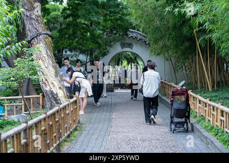Suzhou, China - 11. Juni 2024 : Ein kopfsteingepflasterter Pfad führt durch üppiges Grün im Garten des bescheidenen Administrators in Suzhou, China. Stockfoto