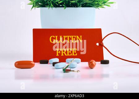 Phrase Glutenfrei auf einer roten Karte geschrieben, mit Pillen, Vitaminen im Vordergrund auf weißem Hintergrund Stockfoto