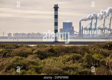 Europort, Hafen Rotterdam, Südholland, Niederlande - 15. November 2022: Ein Containerschiff verlässt den Hafen und überquert einen Leuchtturm Stockfoto