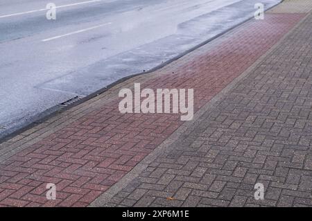 Nasse Straße, Bürgersteig, Radweg mit Verkehrsschildern Stockfoto