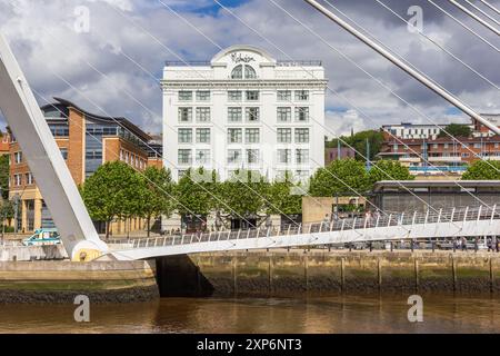 Gateshead Millennium Bridge vor einem weißen Gebäude in Newcastle upon Tyne, England Stockfoto
