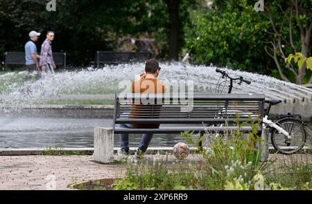 Köln, Deutschland. August 2024. Ein Mann ruht auf einer Parkbank im Rheinpark. Meteorologen prognostizieren für die kommende Woche eine Mischung aus Regen, Sonne und Wolken. Quelle: Roberto Pfeil/dpa/Alamy Live News Stockfoto