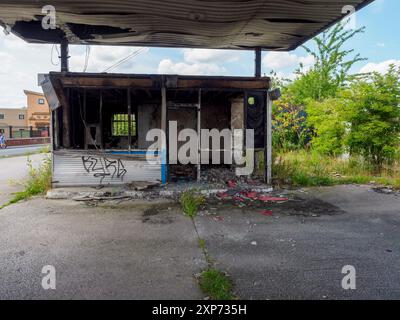 Verlassenes und mit Graffiti bedecktes kleines Gebäude in einem städtischen Gebiet unter klarem Himmel. Wigan UK. Stockfoto