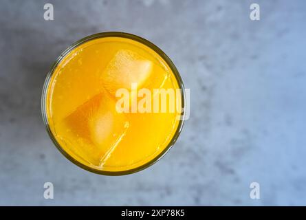 Ein Glas frischer Orangensaft mit Eis auf dem Tisch am Morgen Stockfoto