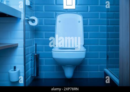 Bad und Toilette mit blauem Licht in der Nacht, Apartment- oder Hoteleinrichtung mit WC. Stockfoto