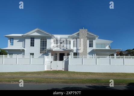 Ein großes zweistöckiges modernes Haus mit Steinkamin, Portikus, Giebeldach, hohen Fenstern, Vorstadtarchitektur in Camp Hill, Brisbane Stockfoto