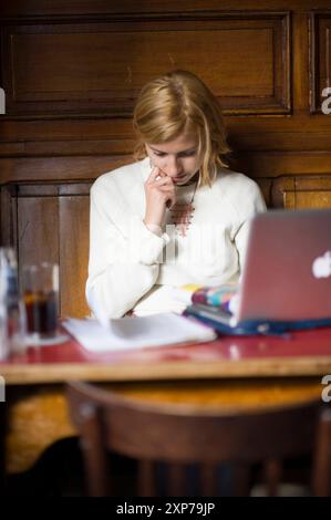 Junge, Blonde Frau in Cafe Young, Blonde Frau in Cafe Westerpaviljoen arbeitet hart an Lernaufgaben. Rotterdam, Nehterlands. MRYES Rotterdam Wester Paviljoen Zuid-Holland Nederland Copyright: XGuidoxKoppesxPhotox Stockfoto